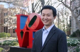 Kecheng Fang smiling and posed for a picture in front of the LOVE sign on the University of Philadelphia's campus 