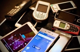 Various phones, smartphones and cell phones arranged on table; photo credit: Eirik Solheim / Unsplash