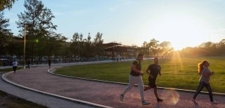 People running and walking on a track. In the center of the track is a green field. The time of the day is either sunrise or sunset. Photo credit for Alex McCarthy, Unsplash.