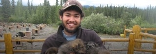 Man holding puppies in Alaskan landscape