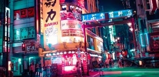 Colorful image of a food area on a street in Hyakkendana, Tokyo, Japan. There are lots of bright signs and lights. It is not busy, as there are only 10 people visible. Photo by Alex Knight on Unsplash.
