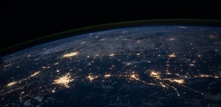Shot of a part of Earth from space. In this section you can see multiple hubs of lights all over which are probably cities. You can also see clouds. Photo by NASA on Unsplash.