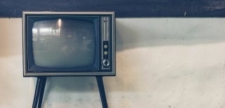 Old-time Sharp television in front of a beige, slightly dirty wall. The tv is off left in the image frame. Photo credit for Sven Scheuermeier, Unsplash. 