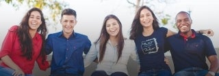 Young people sitting with arms around each other, smiling for the camera; Photo Credit: Naassom Azevedo / Unsplash