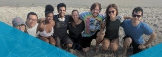 group of people on a beach, posing in a crouched position, smiling for the photo