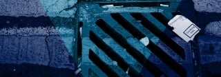 View of street drain with a crushed cigarette box that reads "smoking kills", photo credit iStock / johnnyscriv
