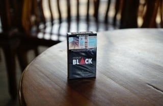 cigarette pack with pictorial warning standing on a wooden table, photo credit Afif Kusuma / Unsplash