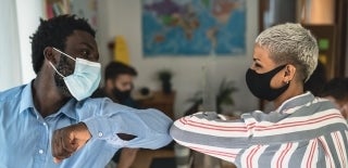 two people wearing masks elbow bump; photo credit: Alessandro Biascioli / Shutterstock