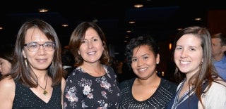 Four staff members posing for a photo in a dark room