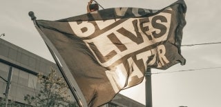 Black Lives Matter flag flying in air; Photo Credit: Clay Banks / Unsplash