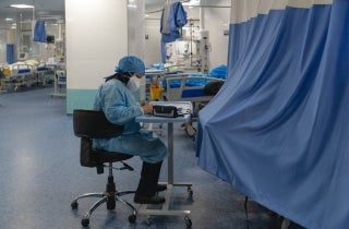 Seated nurse in hospital setting wearing scrubs and face mask