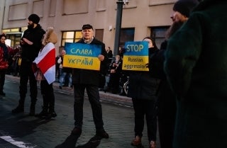 Two protestors holding signs with Ukranian flag colors on them: "Free Ukraine" in Ukranian and "Stop Russian Aggression" in English