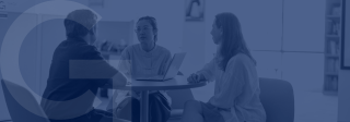 Three people sitting at an office table and talking