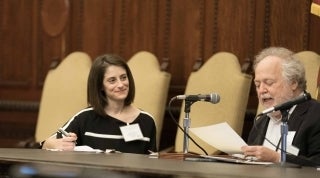 Julia Ticona City Hall 1920 x 1070.jpg Two people sitting behind a table with ornate wood panelling behind them. One of them is speaking into a microphone while the other looks on smiling