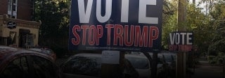 View of West Philadelphia street with cars and signs posted that say "VOTE STOP TRUMP"