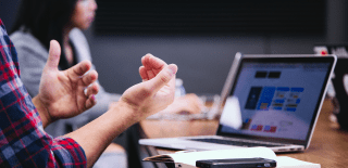 Person in front of computer at meeting teaching and collaborating