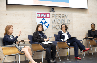 Antonia M. Villarruel addresses the audience while Emily Hannum, Tulia Falleti, and LaShawn Jefferson look on. A sign behind the group reads: Perry World House.