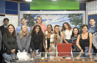 Penn students pose in front of a green screen in a TV broadcast studio 