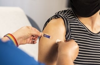 A health care provider places a bandage on the injection site of a patient who just received an influenza vaccine.