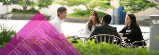 Four people sitting at an outdoor table and talking