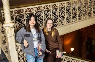 Gemma Hong and Sophie Young standing together holding copies of their book.