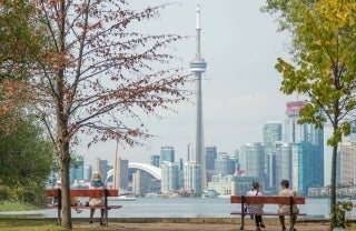 3 people on benches looking out at Toronto skyline.