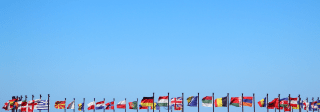 An assortment of flags on flag poles against a blue sky