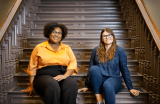 Teia Hudson and Miraya Gesheva sit on steps.