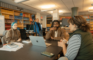 Nya Mbock, Terrence Topping-Brown, Anna Gamarnik, and Waldo Aguirre sit at a table in the Annenberg library