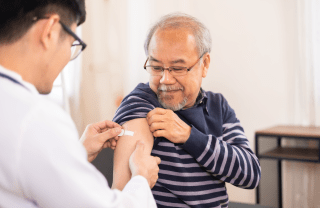 A doctor puts a bandage on a patient's arm after a vaccination