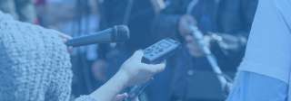 Microphones and audio recorders being held up to an interviewee.