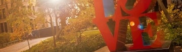 Love 1920 x 550.jpg View of trees and buildings on campus with LOVE statue in the foreground
