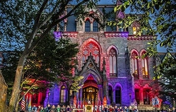 Penn's College Hall lit up in red and blue lights; Photo Credit: Eric Sucar, University of Pennsylvania