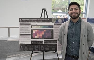 Student standing in front of an academic poster on an easel