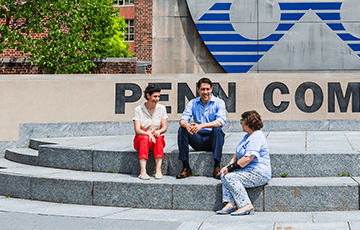 Three people sitting together on the steps at Penn Commons
