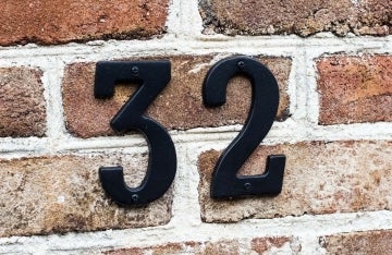 black number 32 on a brick wall; photo by Adrian Curiel on Unsplash