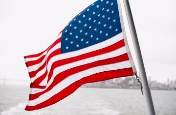 American flag waving in the wind; Photo by Charlotte Harrison on Unsplash