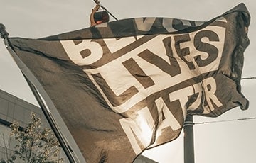 Black Lives Matter flag flying in air; Photo Credit: Clay Banks / Unsplash