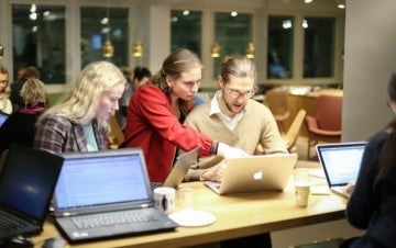 Three Wikipedia editors gathered around open laptops