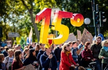 Group of protestors, one of whom holds a large 3D sign saying 15 degrees C, with a red to yellow gradient