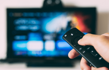 Person holding remote to control TV