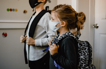 Two children standing side by side wearing masks