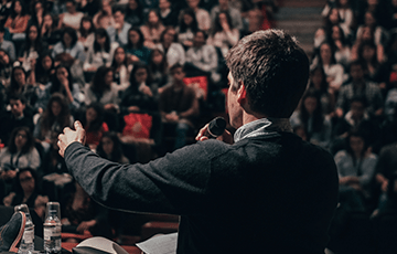 Man speaking in front of a large audience. Miguel Henriques / Unsplash