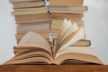 Image of books, one book is open in the foreground 