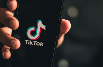 Hand holding a smartphone with the TikTok logo on the screen