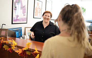 Woman at front desk smiling at an employee