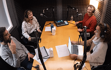 Four people in a studio recording a podcast