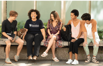 Group of students sitting on a bench, smiling and talking together