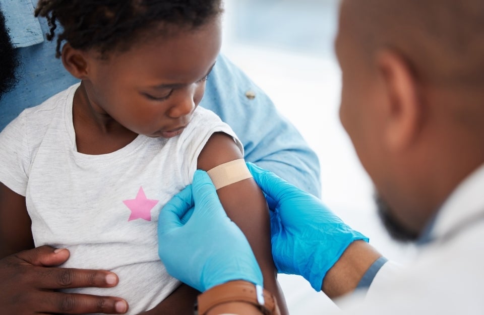doctor applying bandage to a child's arm after a vaccination