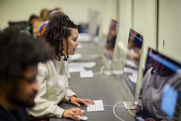 Student sits at computer amid row of other students at computers